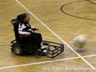 E-Rollifahrerin auf dem Spielfeld mit Ball