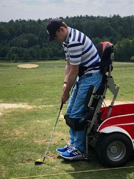 Mensch mit Behinderung beim Golfen im E-Rollstuhl im aufgestelltem Zustand (stehend)
