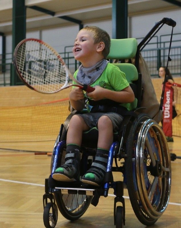 Bub mit Tennisschläger im Rollstuhl