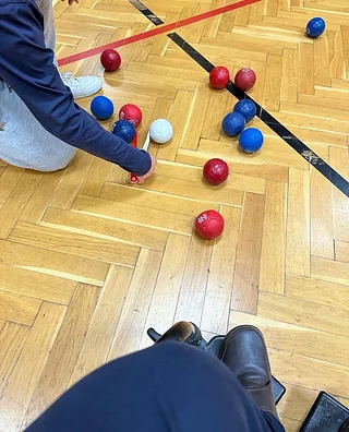 Eine blaue Boccia Kugel wird mit vermessen zur weißen Jack Kugel