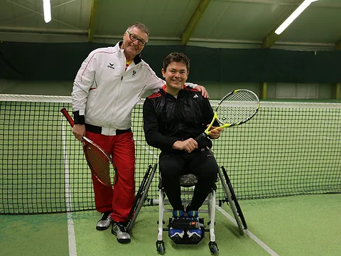 Eine behinderte Person und eine nichtbehinderte Person mit Tennisschläger